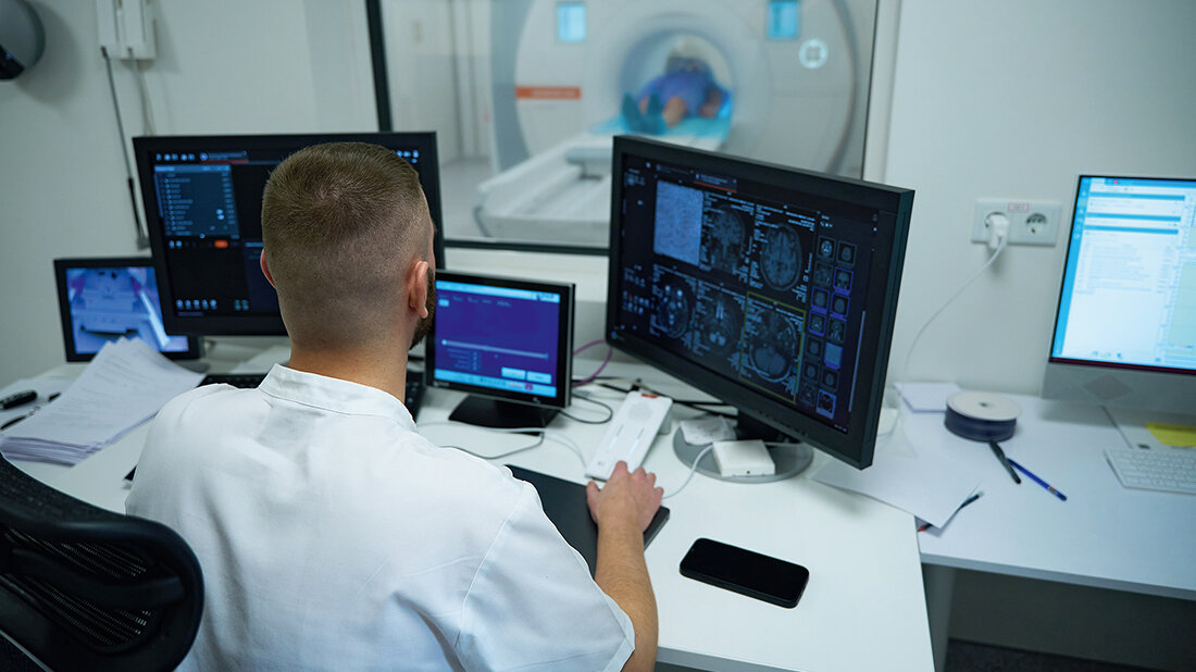 ESCO in der Praxis Foto eines MT an seinem Arbeitsplatz, im Hintergrund ein MRT
