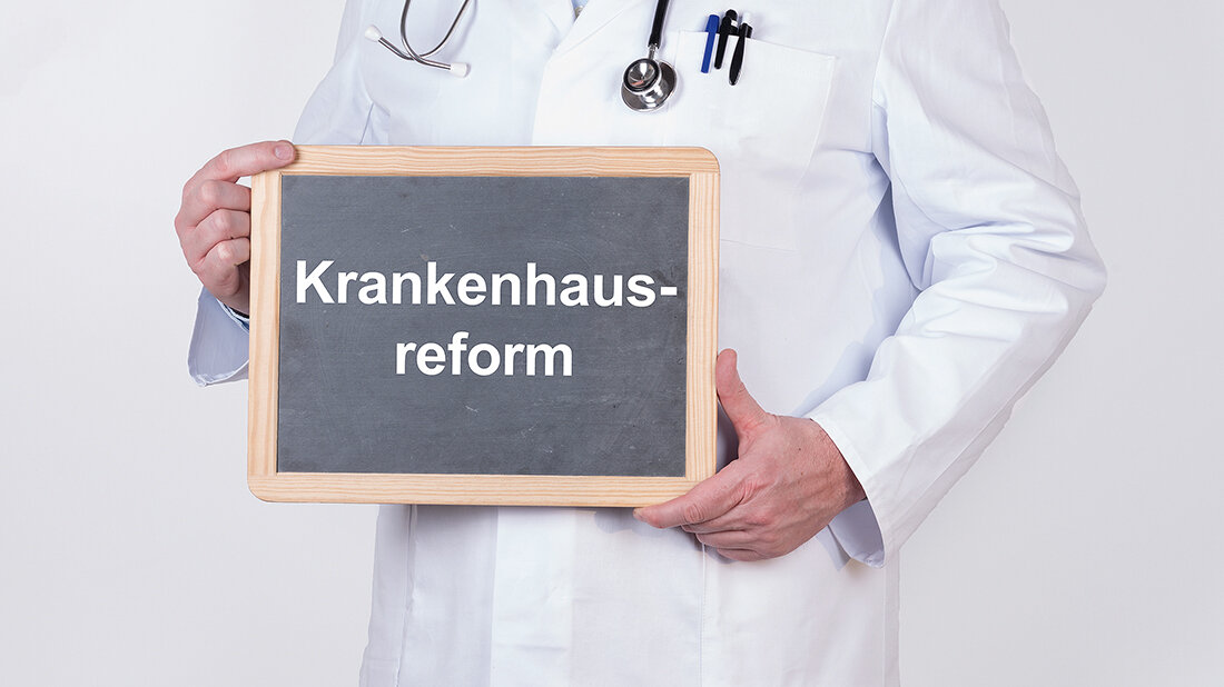 Neues aus der Berufspolitik Mediziner, der eine Tafel hält, auf die das Wort „Krankenhausreform“ geschrieben ist
