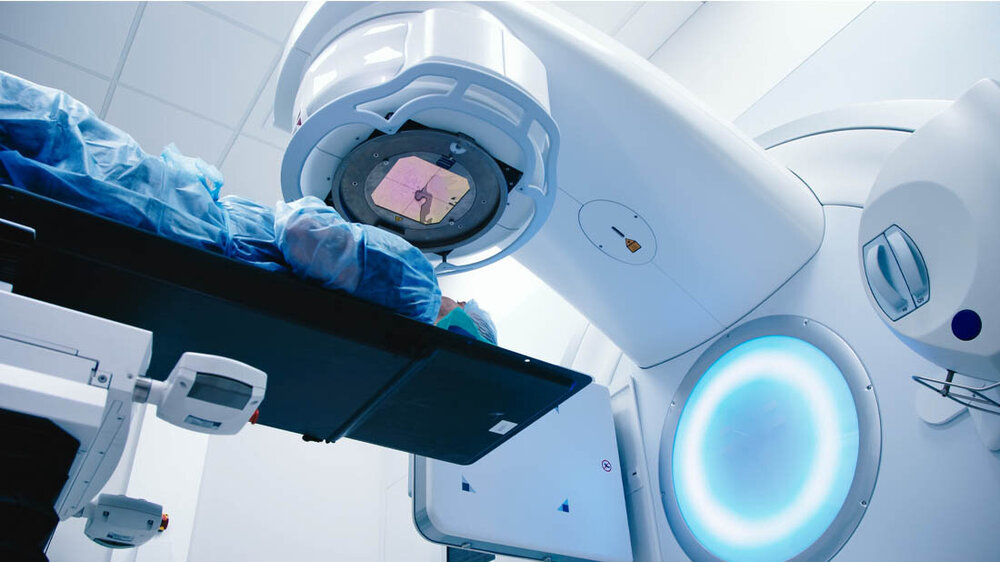 Strahlentherapie_Hautschaden_verhindern.jpg Ein Patient liegt unter einem Strahlentherapiegerät.