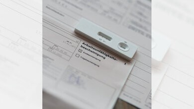 Arbeitsunfaehigkeit_01.jpg Positiver Coronatest, der auf einer Arbeitsunfähigkeitsbescheinigung liegt.