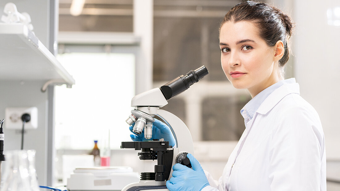 youngDVTA: Deine Ausbildung beginnt – und was du jetzt wissen solltest Foto einer Labormitarbeiterin an einem Mikroskop