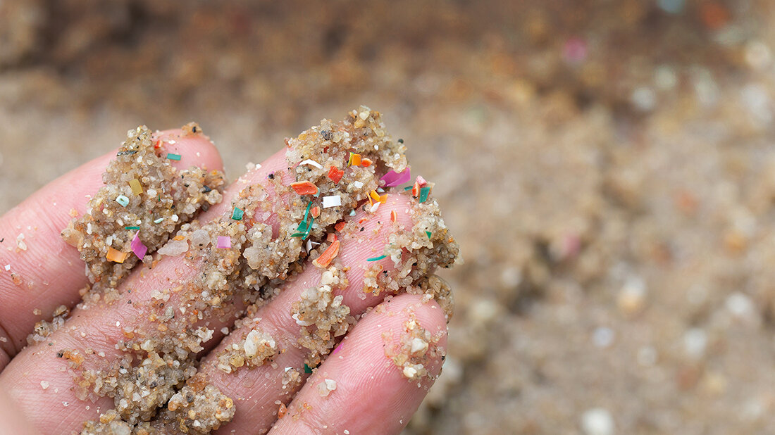 Plastikpartikel in der Blutgefäßwand Foto einer Hand mit einer Mischung aus Sand und Mikroplastik