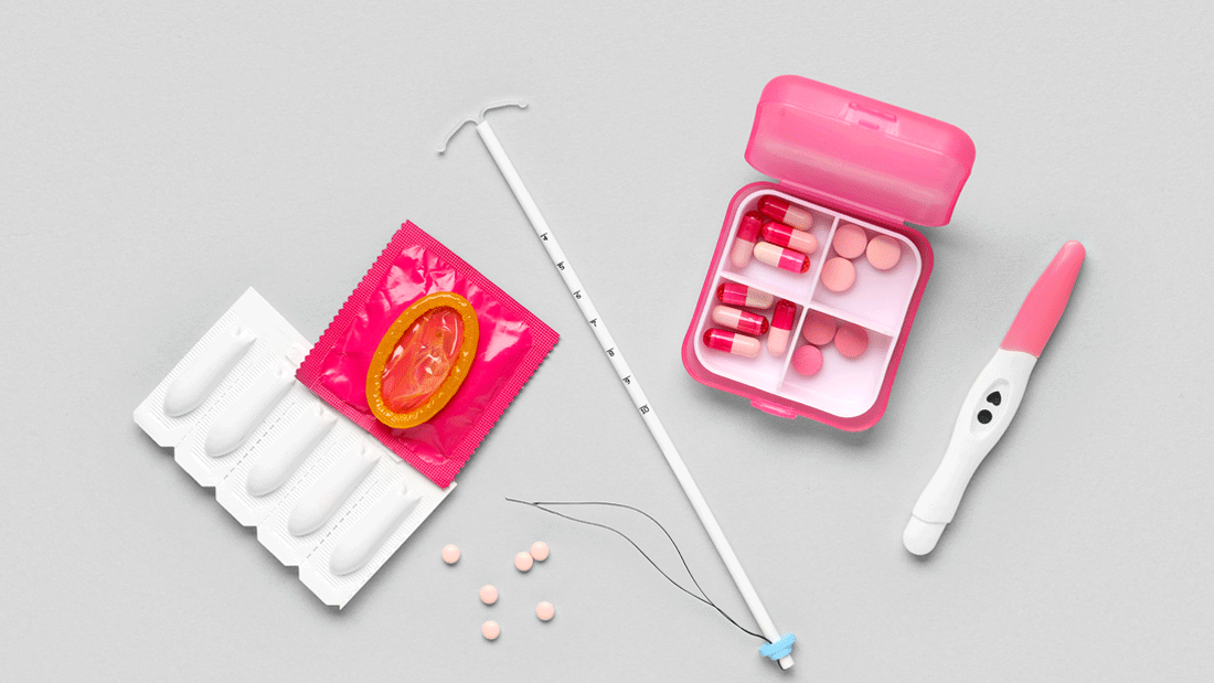 AdobeStock_2154191003.gif Auf grauem Hintergrund liegen Verhütungsmittel: Spirale, Kondom, Vaginalzäpfchen, Pillendose mit Tabletten und ein positiver Schwangerschaftstest.