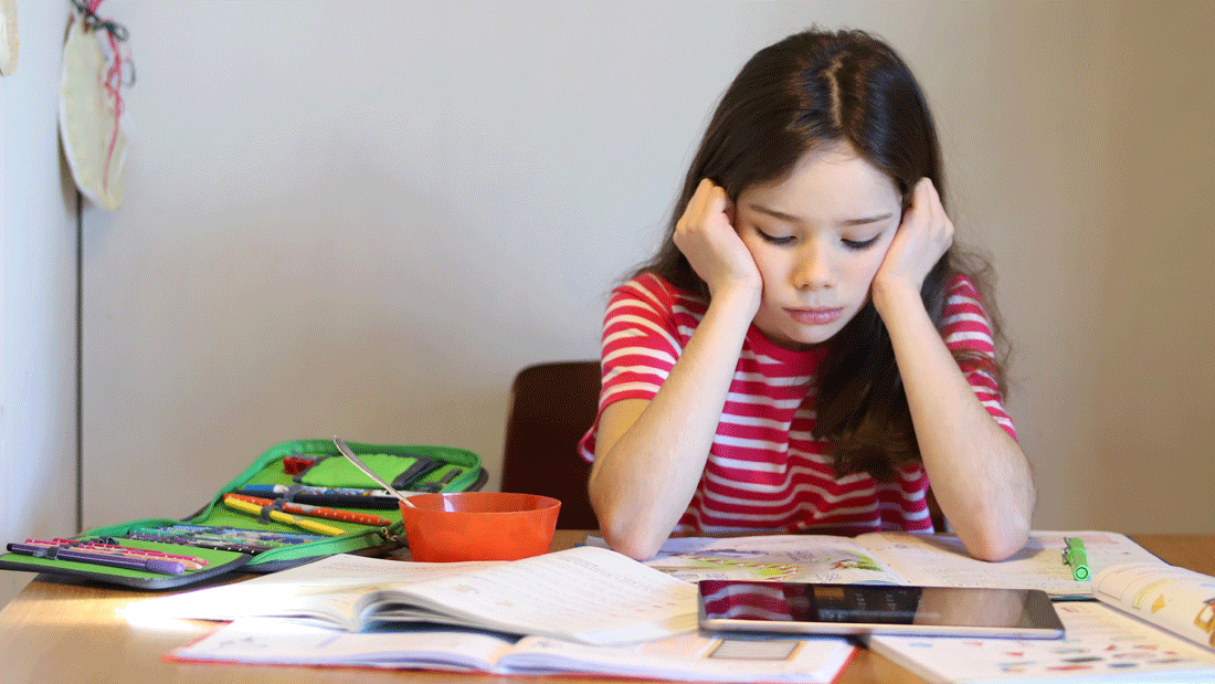 AdobeStock_335884662.gif Ein Mädchen sitzt nachdenklich am Tisch vor Heften, Büchern und Tablet. Neben Schulmaterial steht eine Schüssel.
